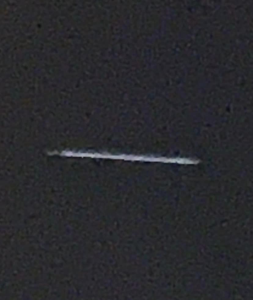 A photograph of a blurry slightly diagonal thin horizontal object on a black background.